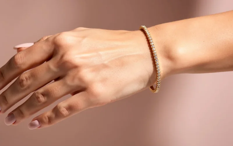 Gold tennis bracelet catching light on a wrist