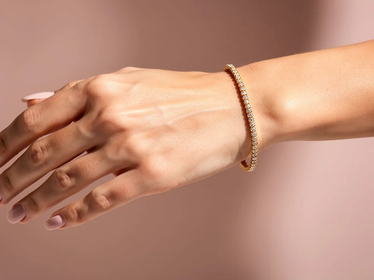 Gold tennis bracelet catching light on a wrist