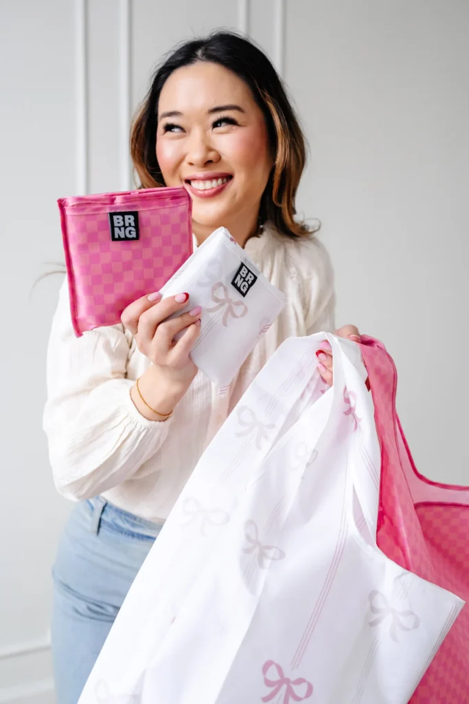 Two reusable shopper totes in pink checks and bows on marble counter