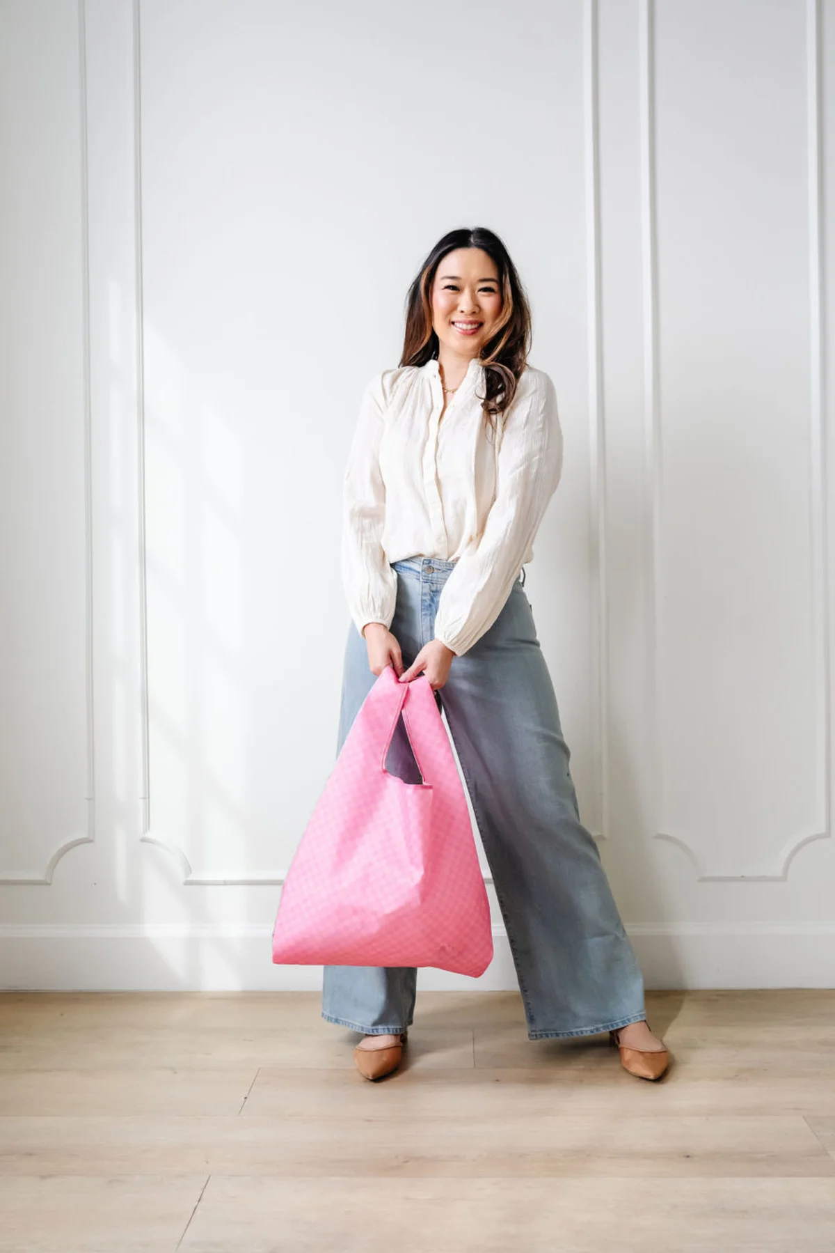Pink checkered Jess tote bag held by woman outdoors