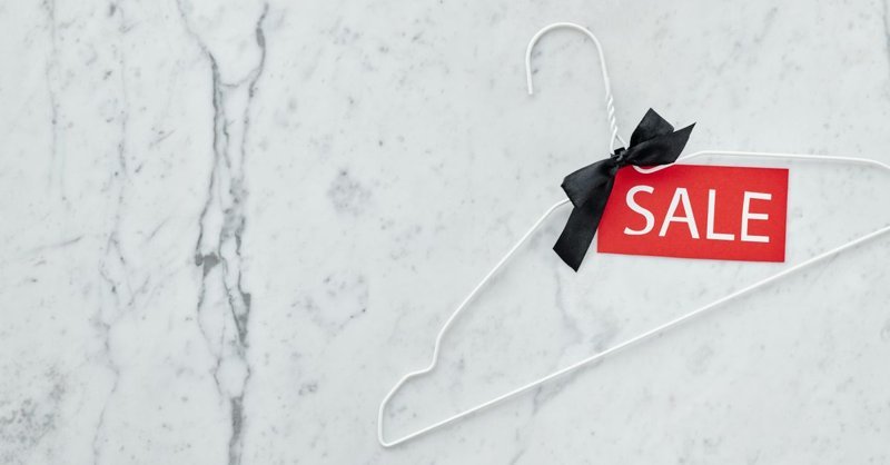 Retail price tag and secondhand price tag pinned on a neutral garment