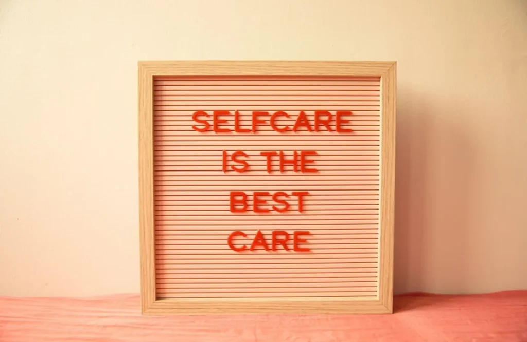 Wooden letter board reading self care is the best care in orange letters